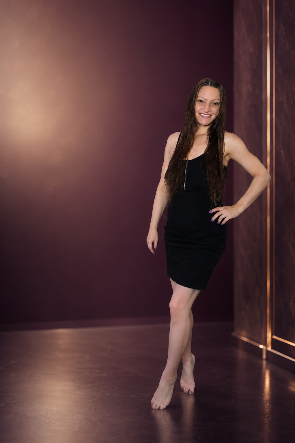 Ren Rose smiling in a black dress in a stage-inspired setting